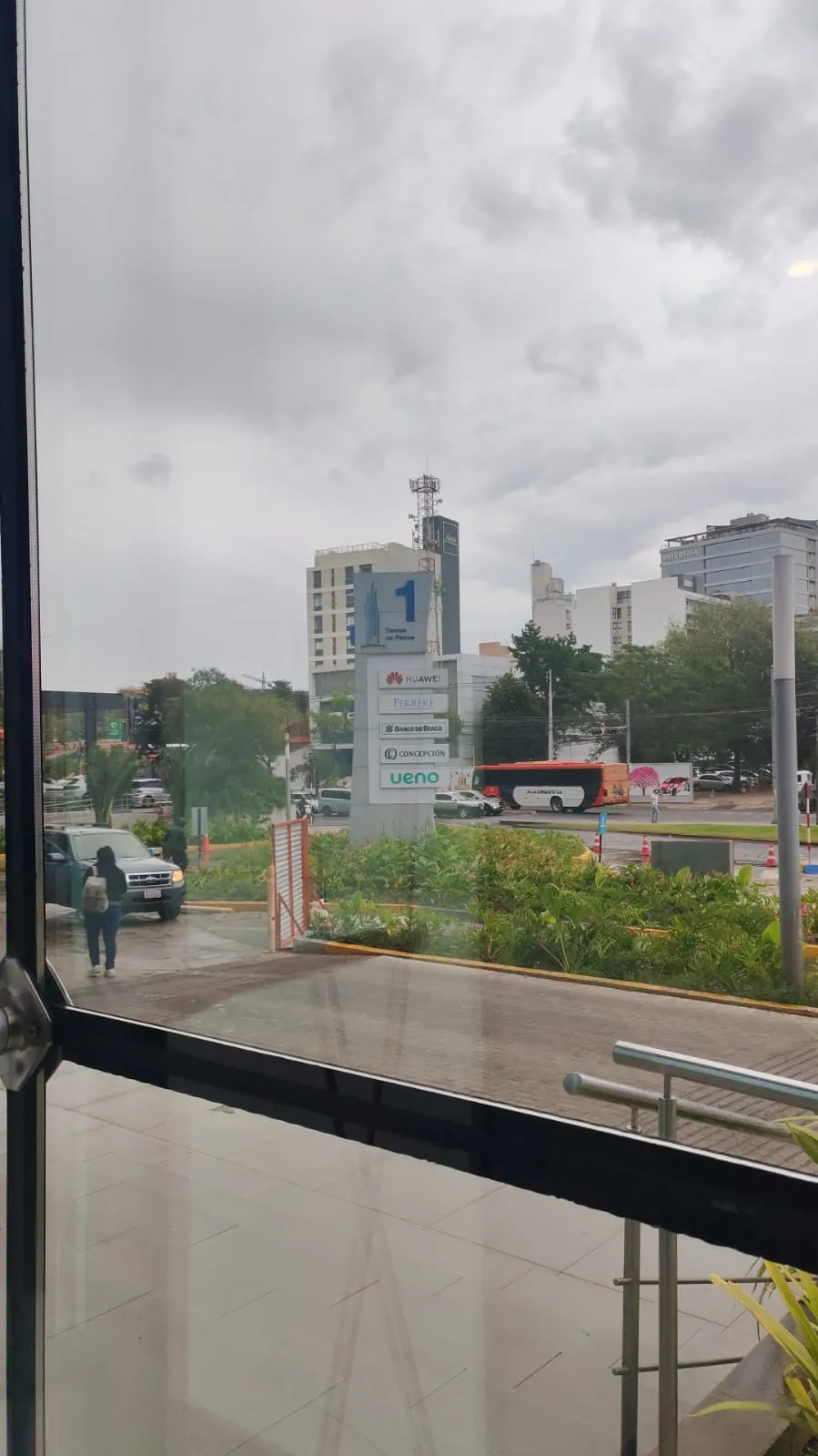 Vista desde la puerta de vidrio hacia la calle y el cartel de ueno en el Paseo La Galería, con el día nublado.